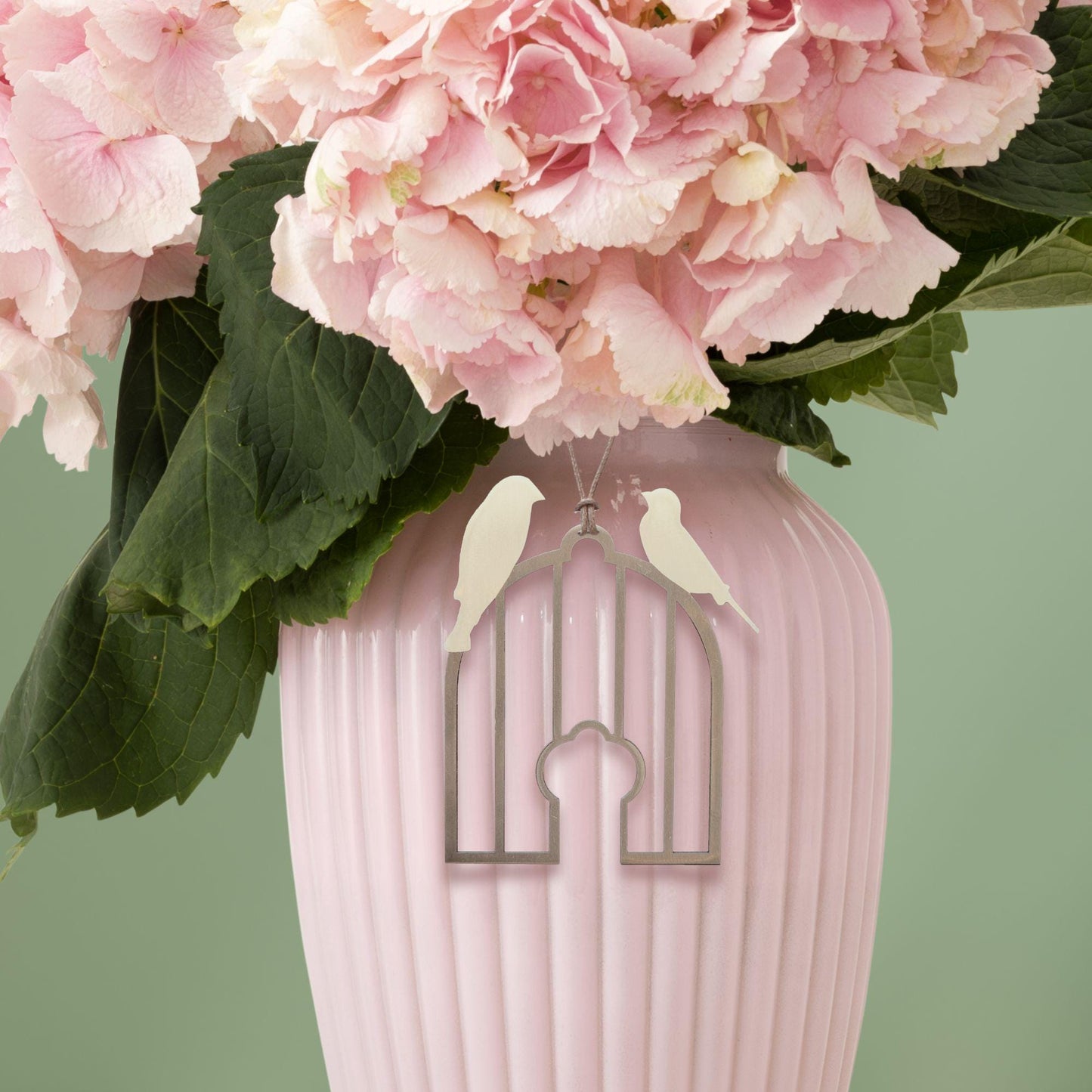 a pink vase filled with pink flowers and two birds