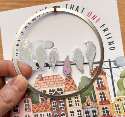 a hand holding a magnifying glass with a picture of birds on a wire