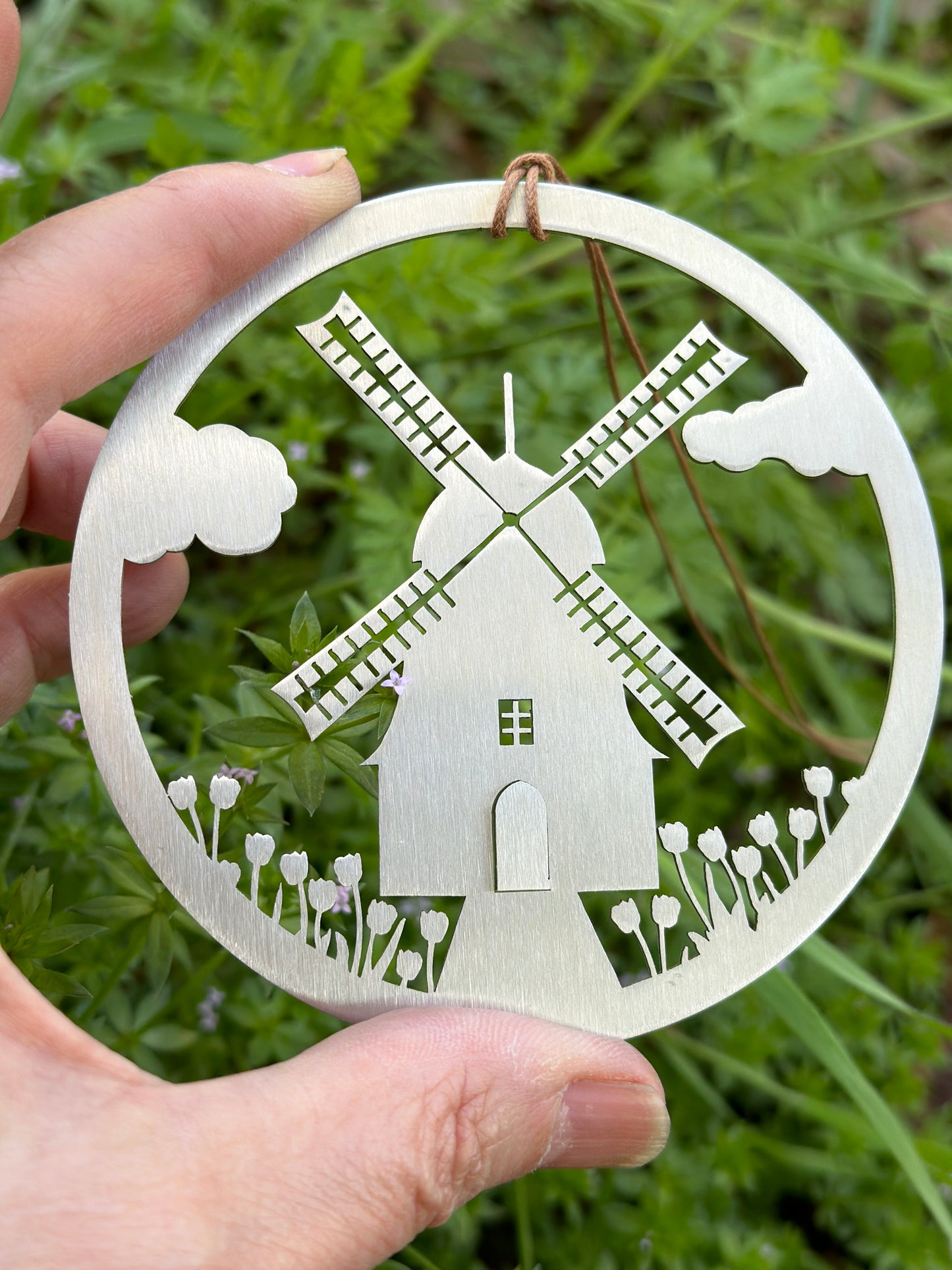 a hand holding a metal cut out of a windmill