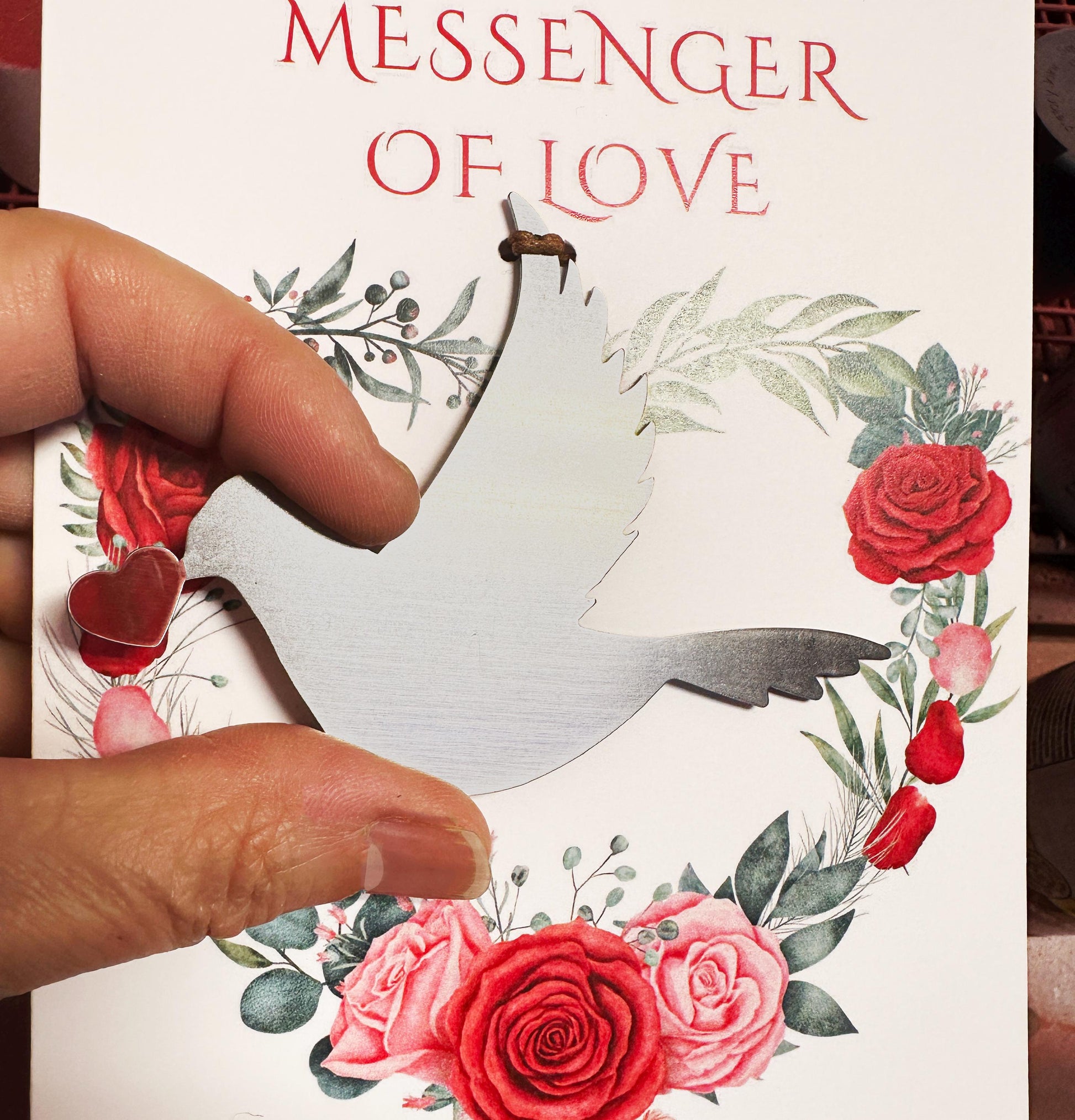 a person holding a dove ornament placed on a love greeting card