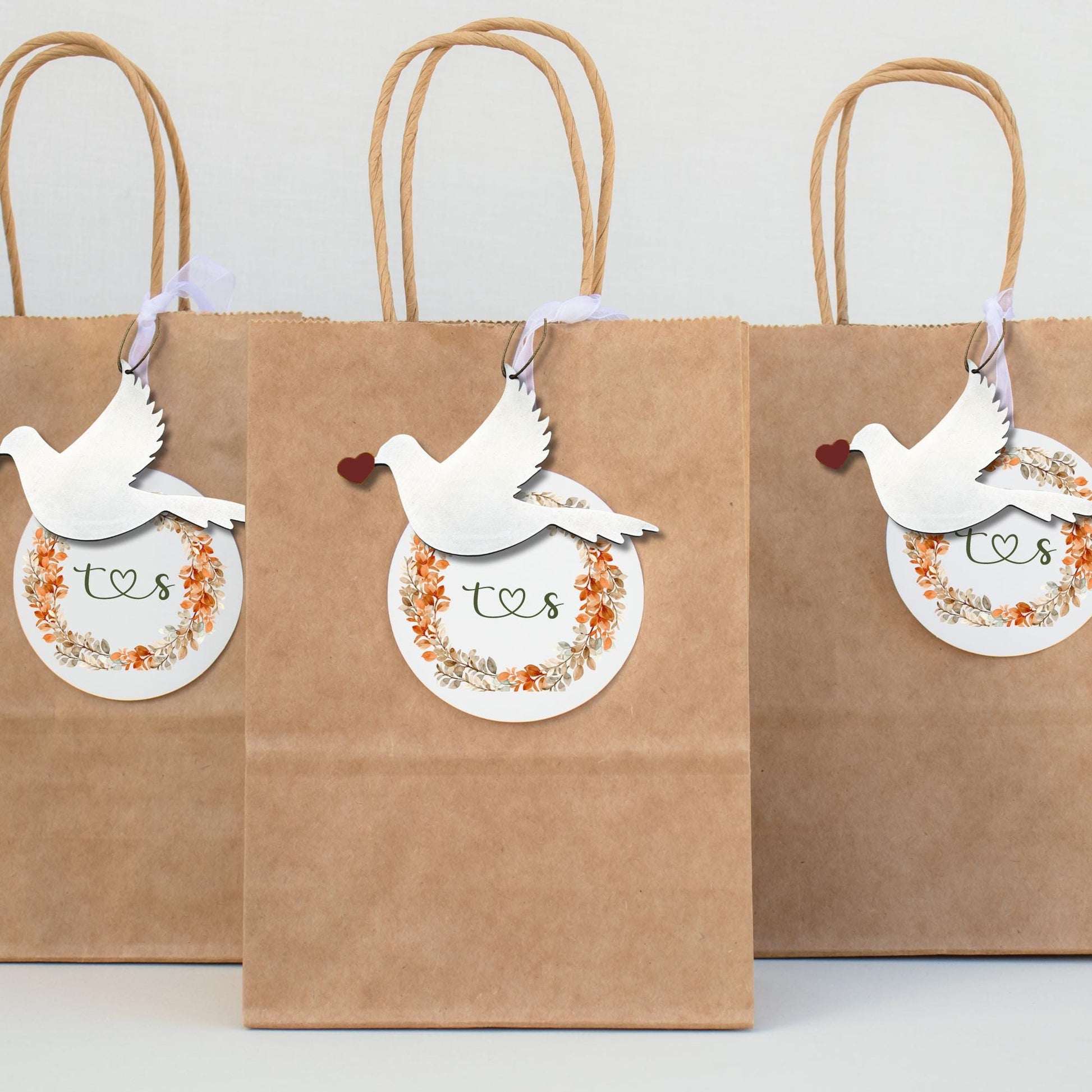 three brown paper bags with stainless steel dove ornaments on them